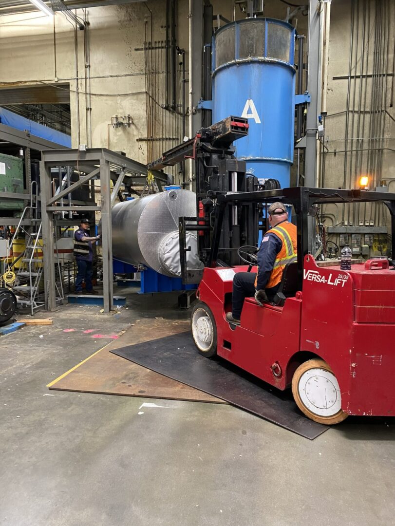 A man driving a red forklift in an industrial setting.